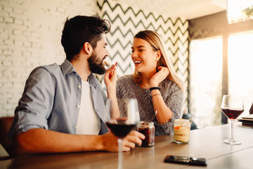 Pretty girl is eating dessert with her boyfriend in cafe, after they drank wine