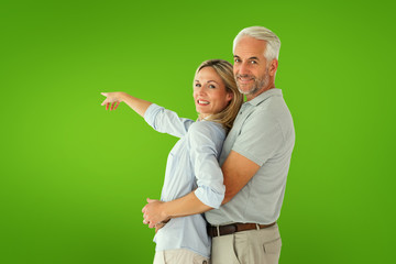 Happy couple smiling at camera and pointing against green vignette