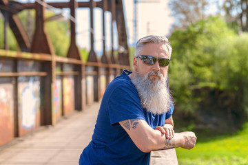 Bearded man in sunglasses standing on a bridge