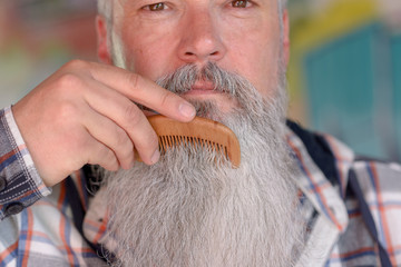 Older man combing his long grey beard