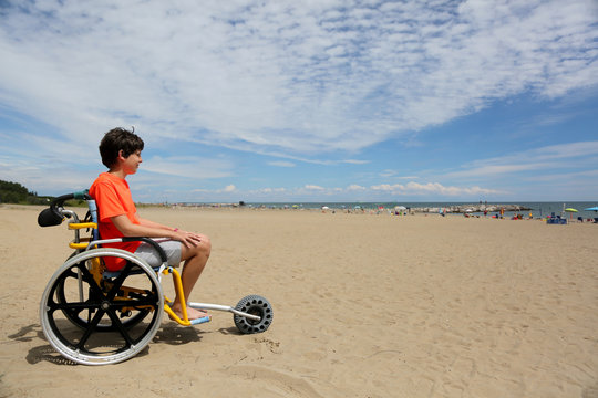 boy with orange t-shirt sitting on the special wheelchair with a