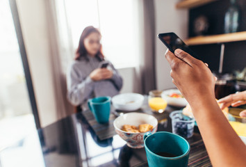 Fototapeta na wymiar Couple eating breakfast whilst using mobile phones