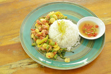 spicy stir fried fermented sour pork with basil leaf and plain rice on plate