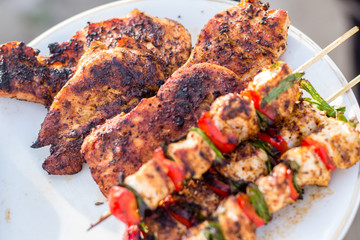 Close up pf delicious chicken breast on wooden skew with fresh vegetables, garlic, paprika fried on mangal barbeque grill