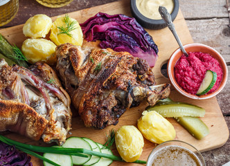 Close view of baked pork shank with appetizers and beer