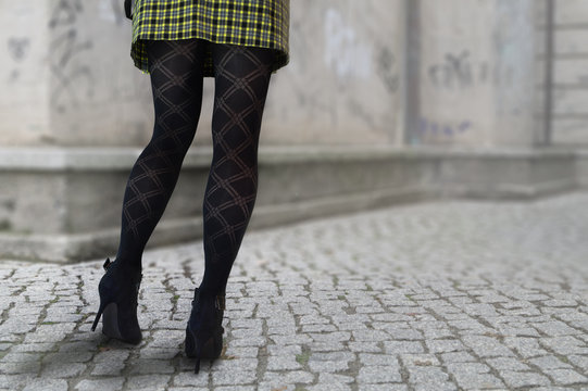 Frau in High Heels, schwarzen Strümpfen und Faltenrock.