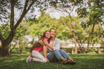 Naklejka na ściany i meble Portrait of Young Happy Beautiful Mother and Daughter Hugging. Embrace in Sunny Day on Meadow