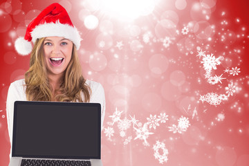 Festive blonde showing a laptop against red design with white snowflakes