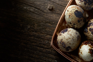 Obraz premium Quail eggs in a box on a vintage wooden background, top view, selective focus.