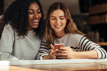 Friends sitting in a cafe looking at mobile phone