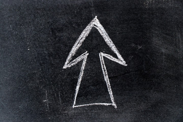 White chalk drawing in arrow shape on black board background
