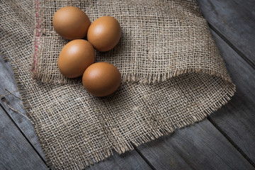 chicken eggs in burlap sack on an old wooden background
