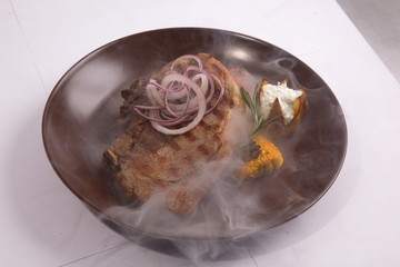 Steak on brown plate with smoke