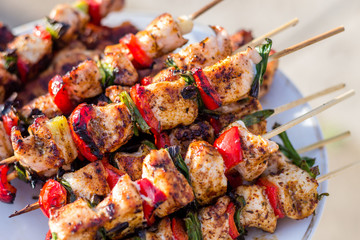 Close up pf delicious chicken breast on wooden skew with fresh vegetables, garlic, paprika fried on mangal barbeque grill