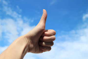 gesture showing thumbs up hand sign on the blues sky with path