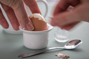 Frau pellt Ei im Eierbecher beim Frühstück
