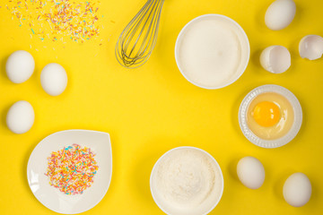 concept of the Easter bakery, various products for home baking, sugar, eggs and flour, coconut munt, top view, empty space for text on a yellow background in the style of pop art mocap layout