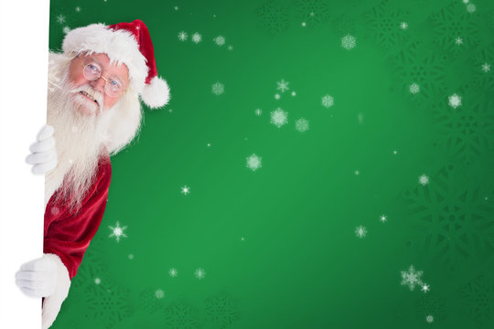 Santa Looks Out Behind A Wall Against Green Snowflake Background