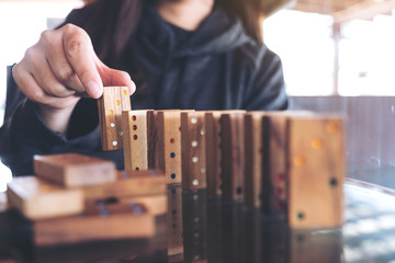 Closeup image of a woman putting wooden domino game in order on table