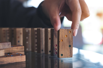 Closeup image of a woman putting wooden domino game in order on table