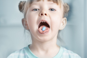 Close up of child puts the pill in his mouth Child is sick with tablet on tongue