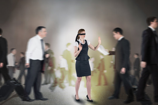 Composite image of redhead businesswoman in a blindfold walking through crowd