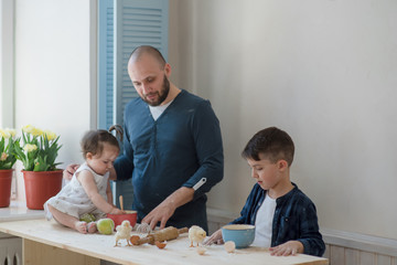 Dad with his little son and daughter baking together.