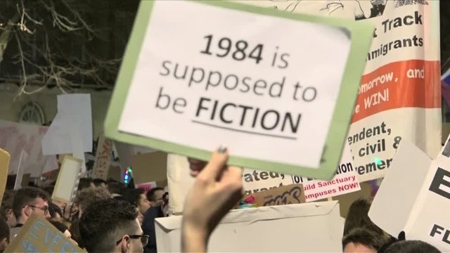 UK January 2017 - A hand holds up a protest placard that says, “1984 is supposed to be fiction”.