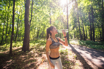 Young woman drinking water after running outdoors
