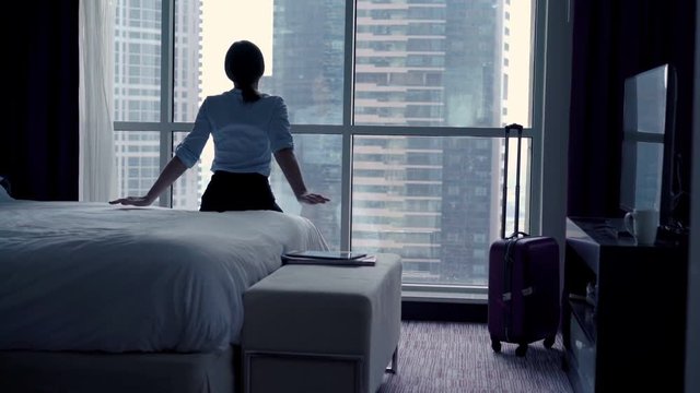 Happy, relaxed businesswoman sitting on bed in the hotel, 4K
