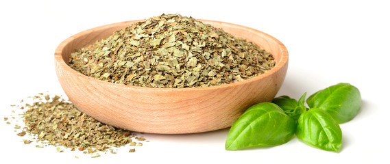 dried basil leaves in the wooden plate, isolated on white