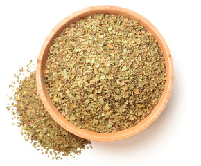 dried basil leaves in the wooden plate, isolated on white, top view