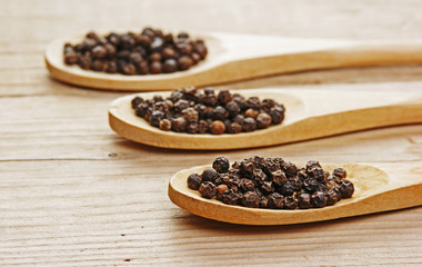 Black pepper in wooden spoon on the old board