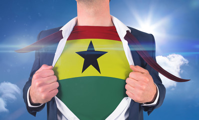 Businessman opening shirt to reveal ghana flag against bright blue sky with clouds