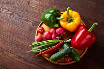 Wooden plate with vegetables for a vegetarian salad on rustic wooden background, close-up, selective focus