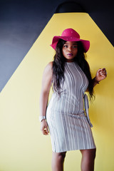 African american woman in hat against black and yellow futuristic wall.