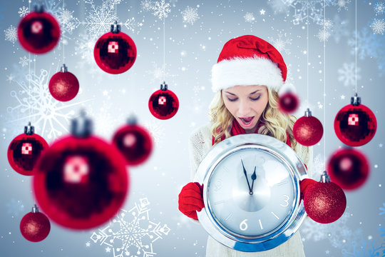 Happy festive blonde with clock against snowflake pattern