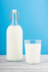 a glass of milk, a bottle of milk on a wooden table 