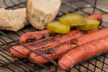 Grill sausage grilled barbecue. Bread and sliced cucumbers. Picnic in the street.