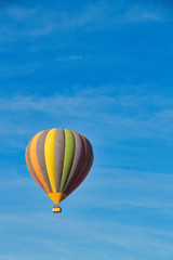 A hot air balloon rising under partly cloudy skies.