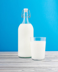 a glass of milk, a bottle of milk on a wooden table 