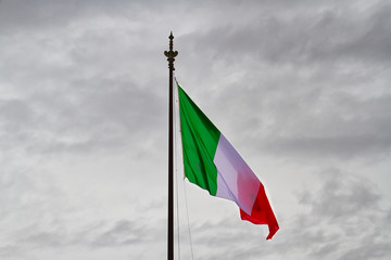 The flag of Italy in a genital breeze and cloudy sky.