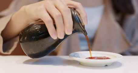 Woman putting soy sauce on plate in Japanese restaurant
