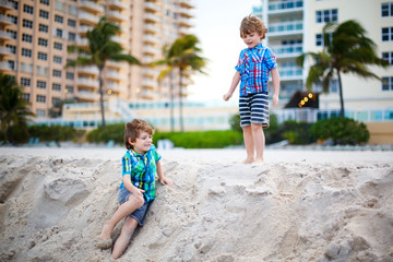 Two little kids boys running on the beach of ocean