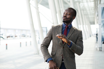 Happy African American business man dances while he listens to the music in his smartphone