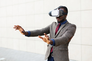 African American business man plays in a VR-glasses standing outside