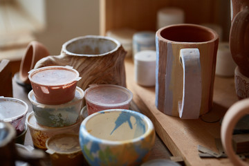Close-up of various paint mugs and brushes in holder on worktop, selective focus, side view.