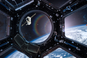 View from a porthole of space station on the Earth background. Elements of this image furnished by...
