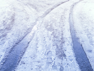 Obraz premium Streams of melted snow on a snowy road tracks in the spring day.