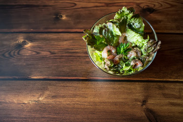 Salad with raw shrimp on wooden background